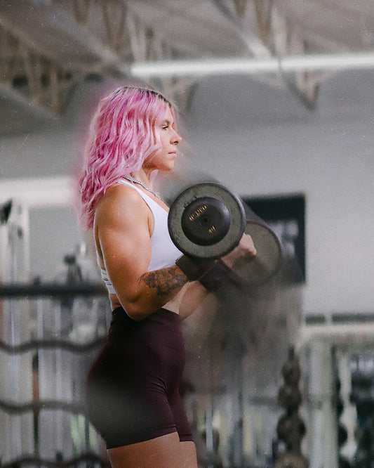 woman doing barbell curls with uppper wrist wraps