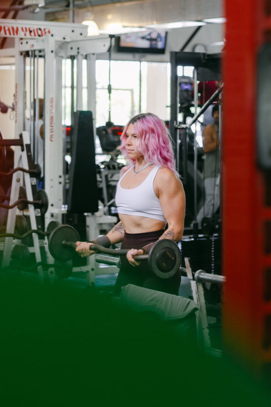 woman doing barbell curls with uppper wrist wraps