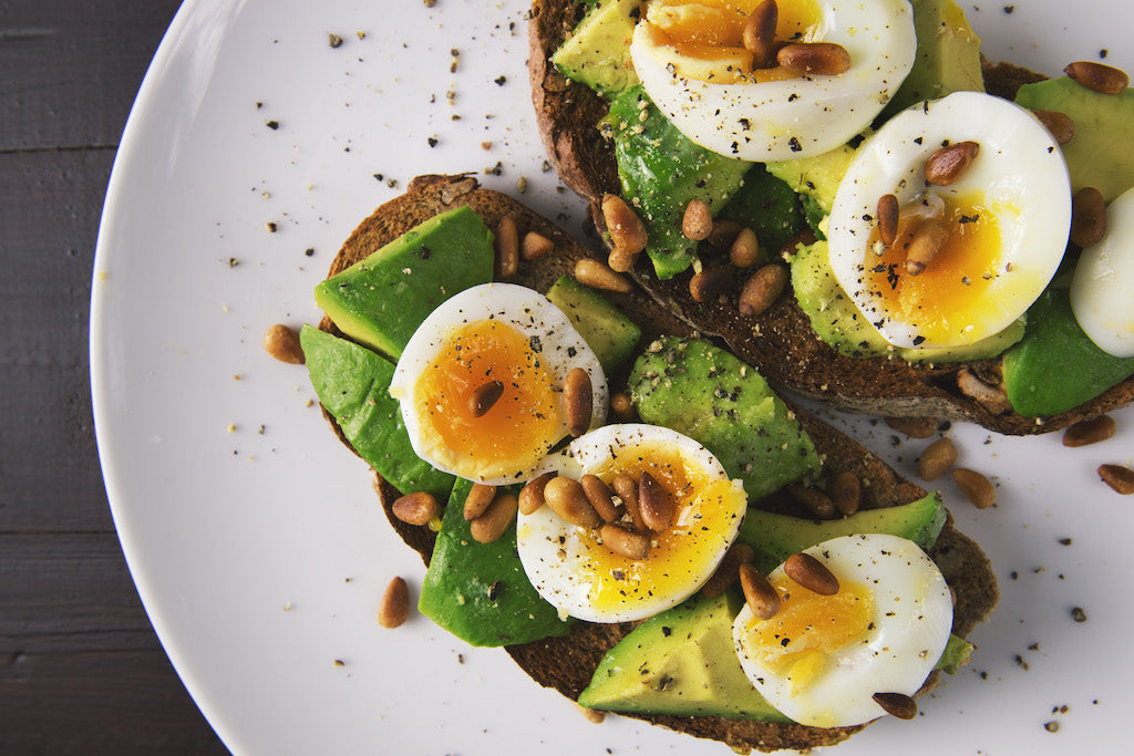 toast topped with avocado, hard boiled eggs, and sunflower seeds