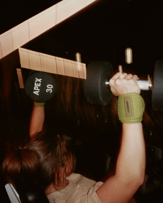 woman doing a shoulder press wearing uppper wrist wraps