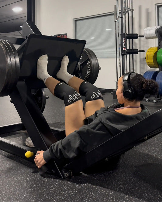 woman doing leg press with uppper knee sleeves