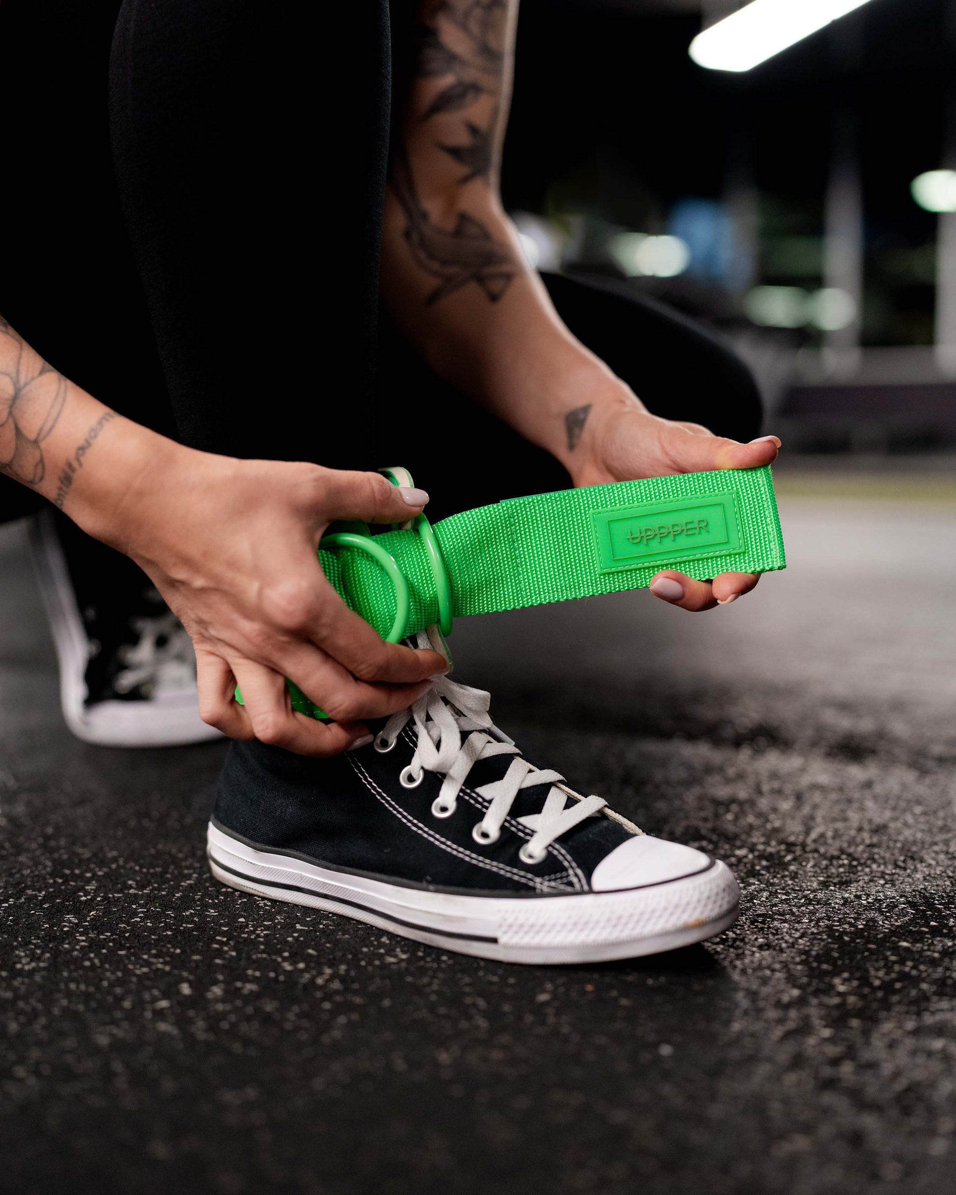 athlete wearing neon green uppper ankle strap on a dark background