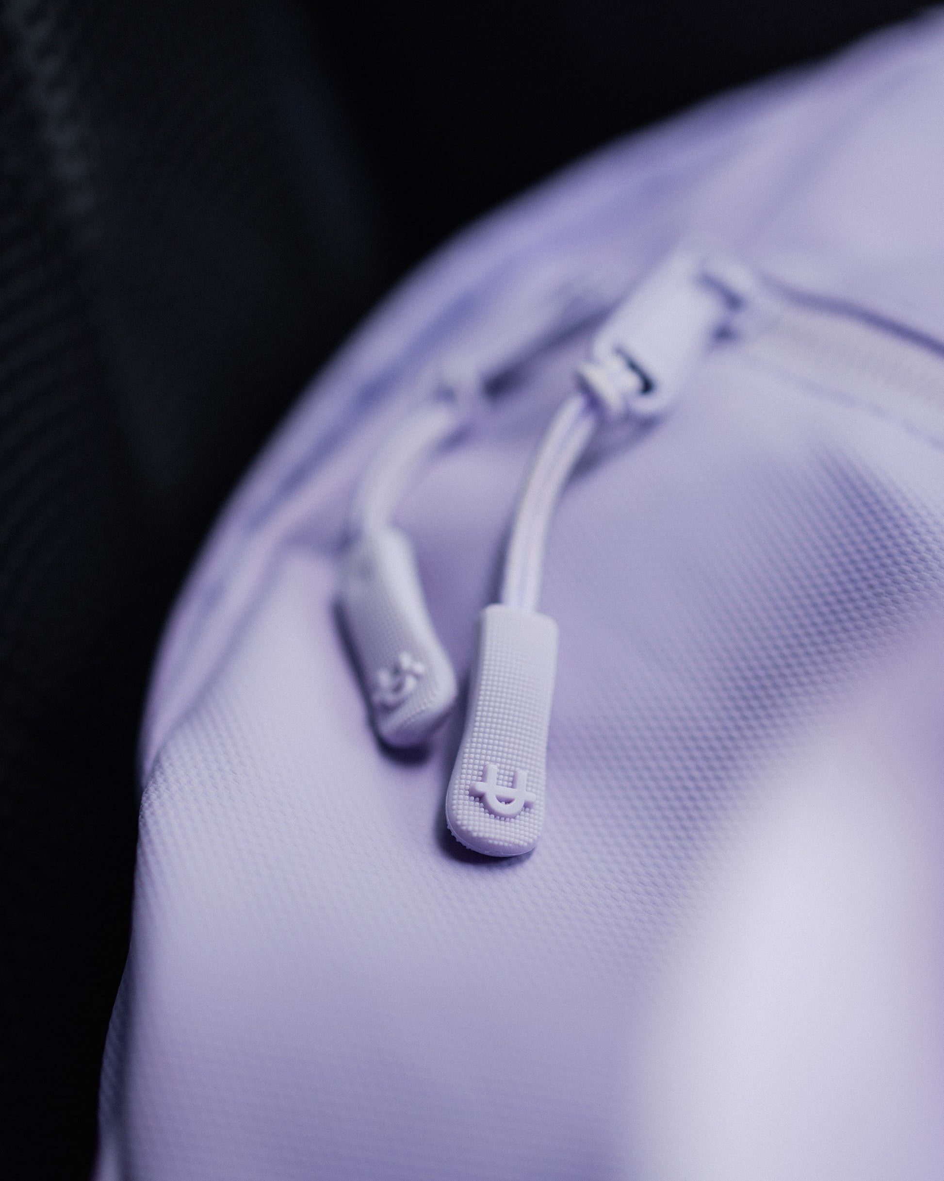 close-up of a lavender upper gym bag with a puller u-logo detail on a dark background