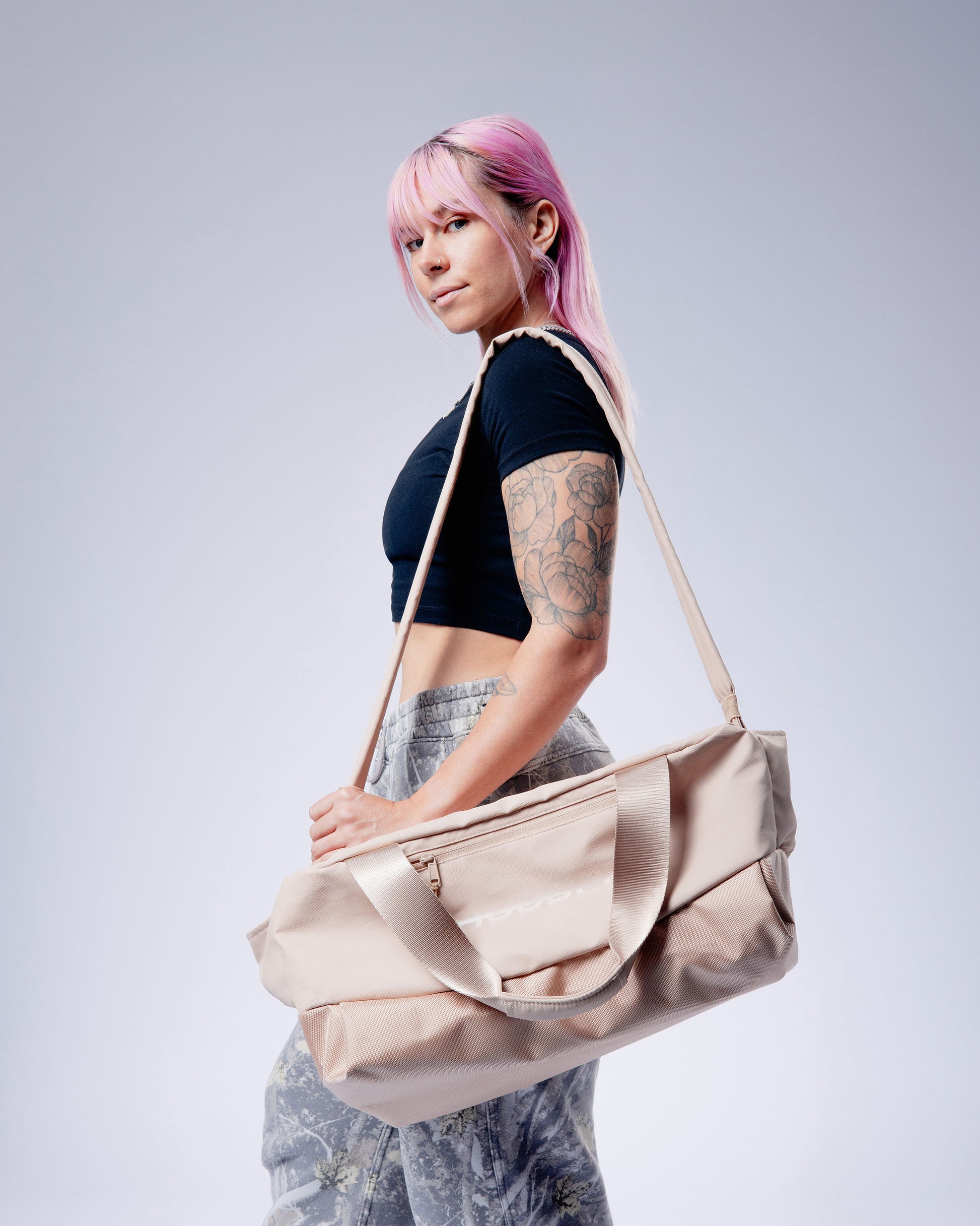 person carrying tan uppper gym bag on a plain background