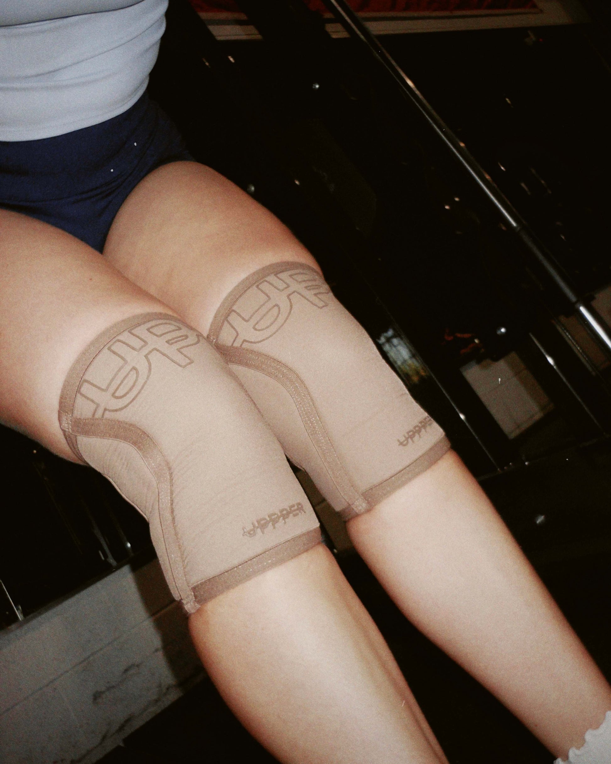 close-up of knees wearing beige uppper knee sleeves in gym environment