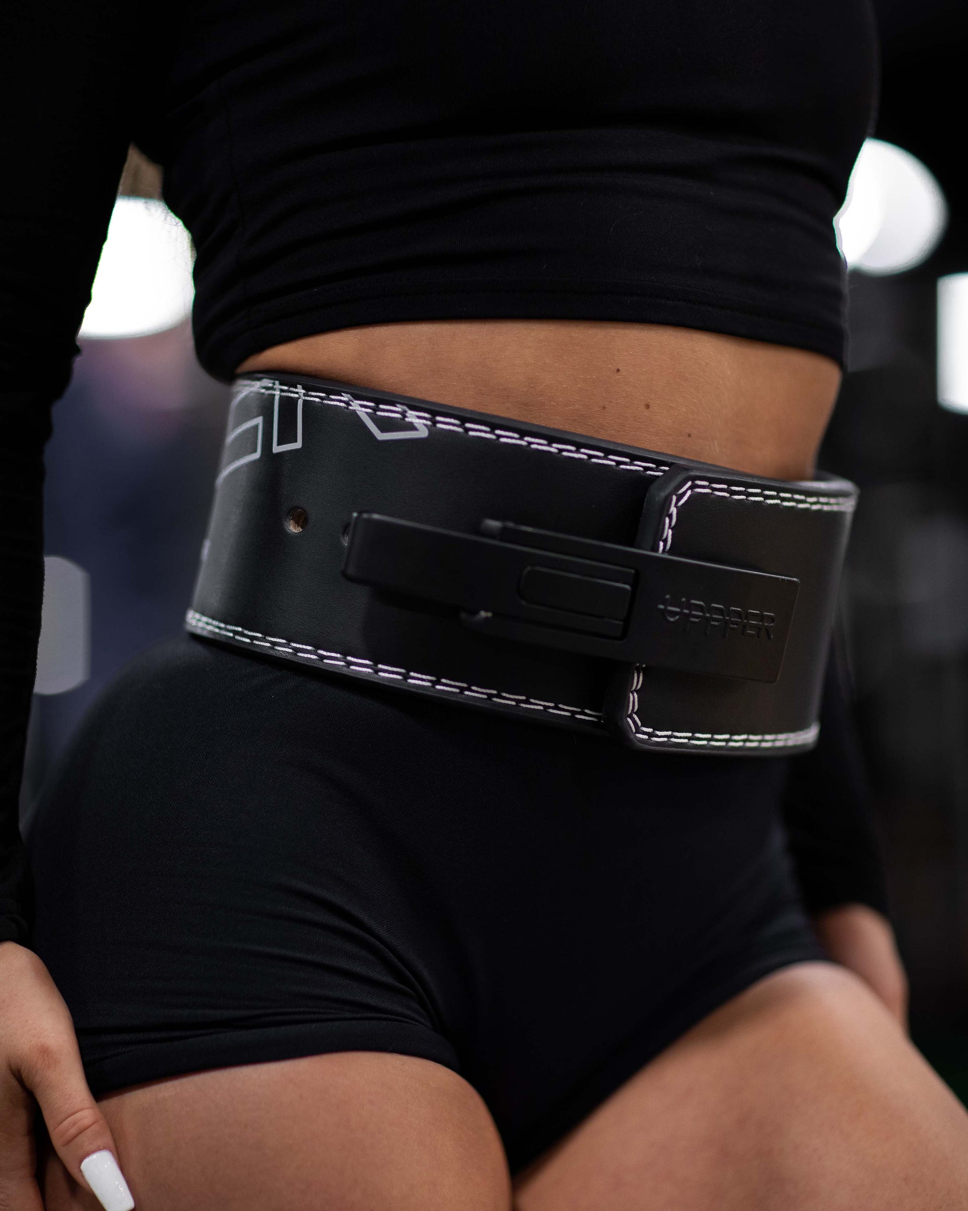 black uppper lever weightlifting belt close-up with stitching and lever buckle worn by a person 