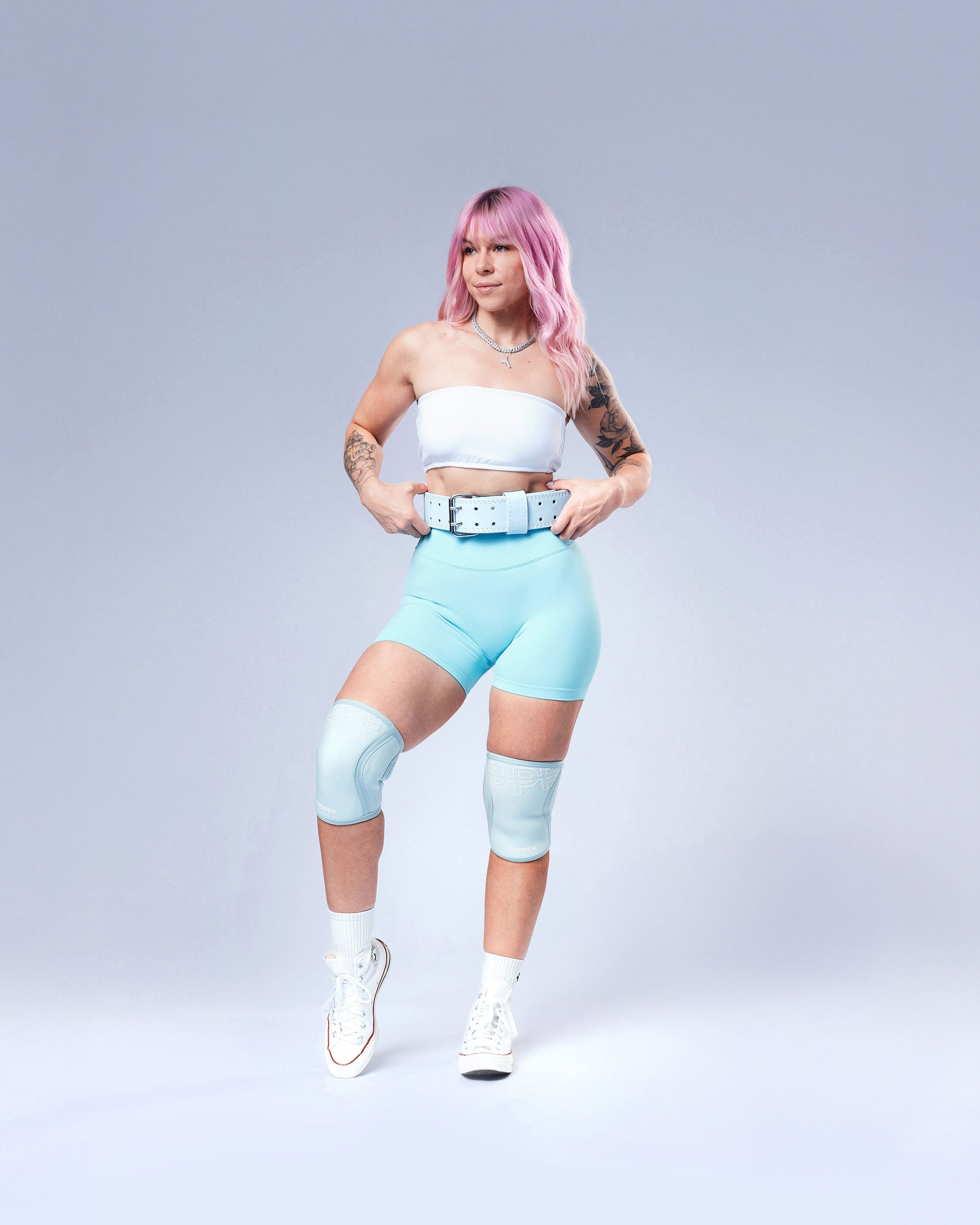 model posing in baby blue uppper lifting belt on grey background 