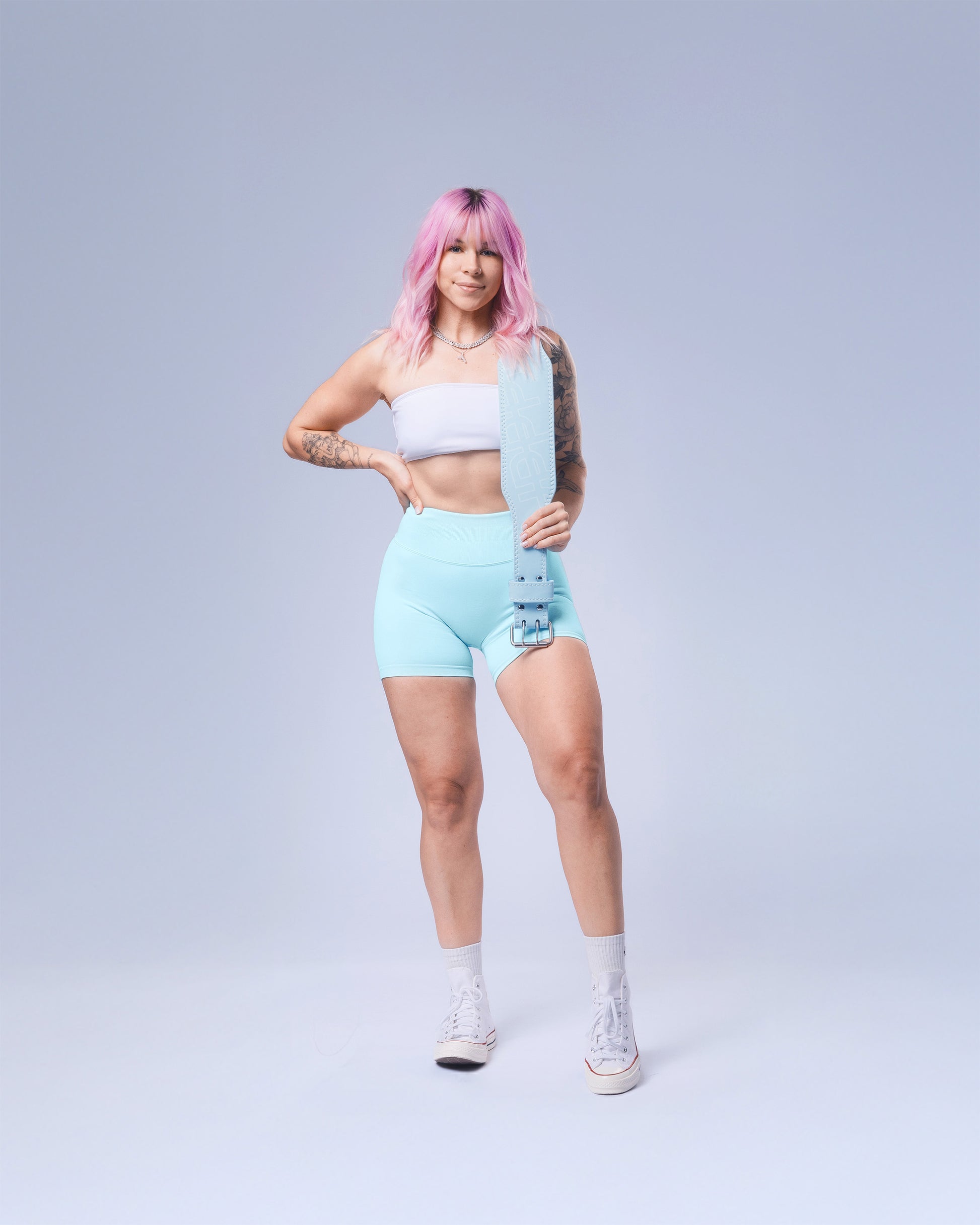 model holding uppper baby blue lifting belt on grey background