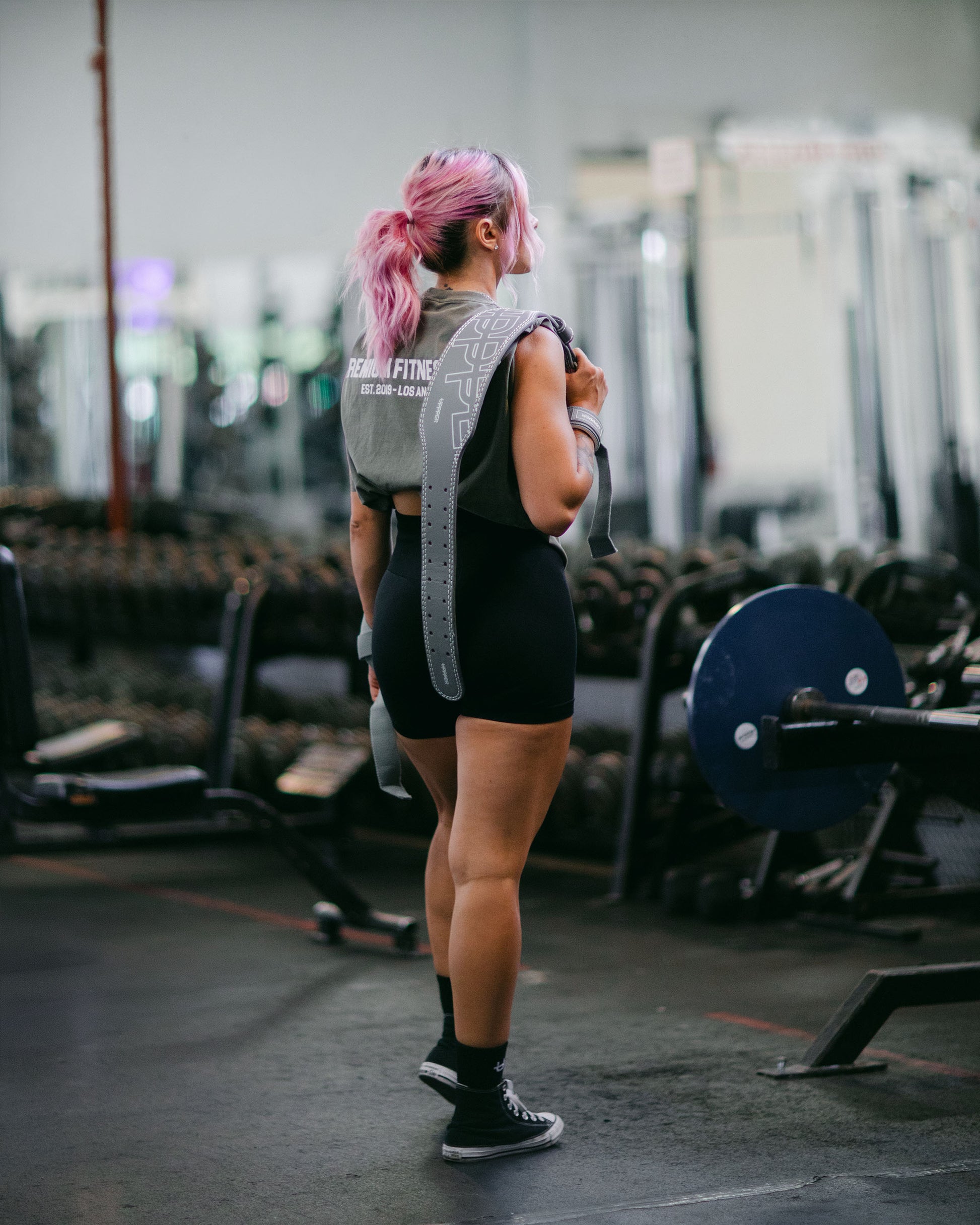 woman in gym posing with uppper lifting belt in grey color