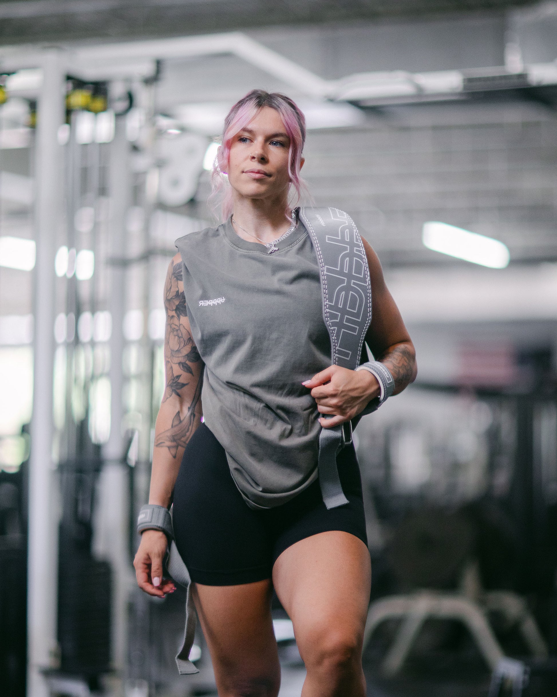athelet in gym posing with uppper lifting belt in grey color showing logo part