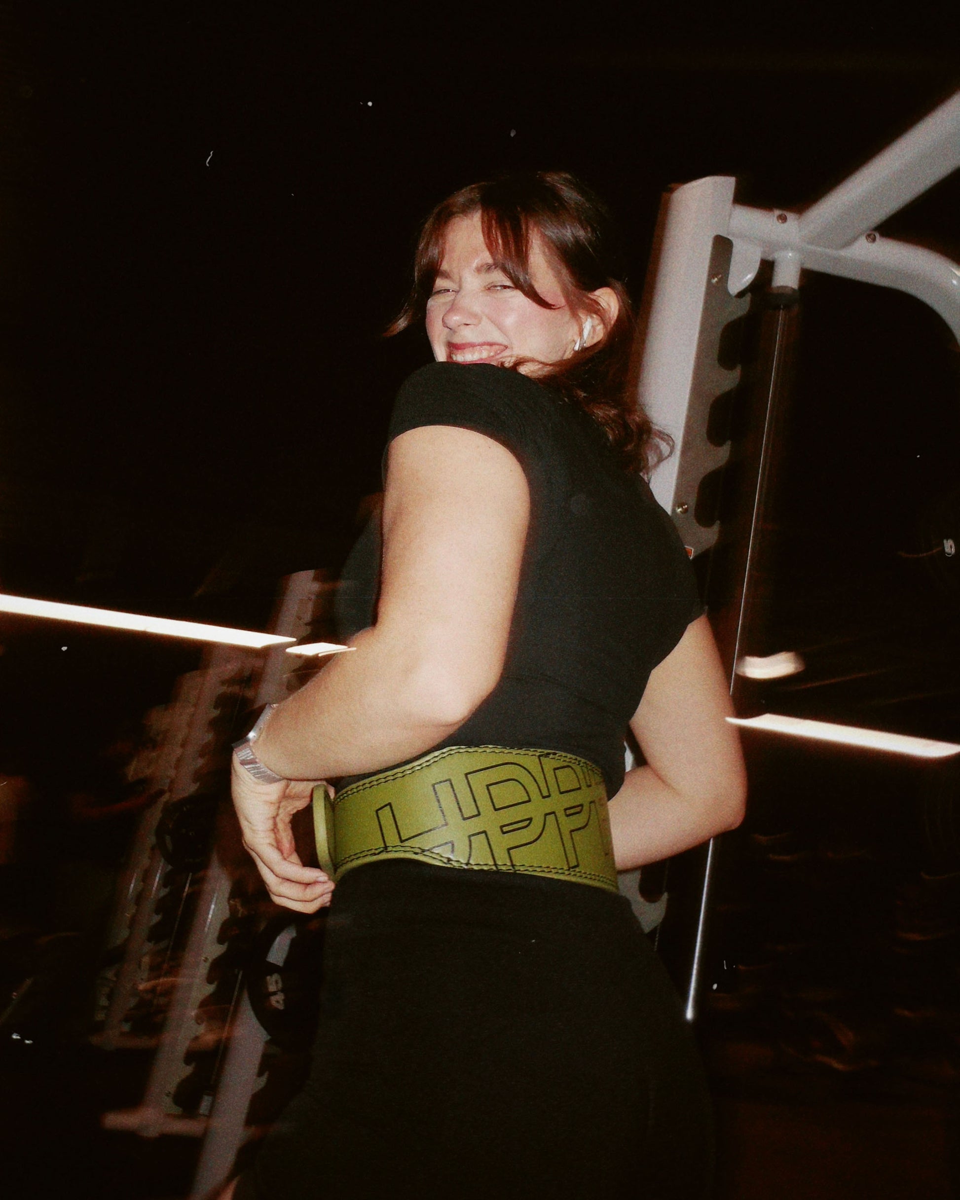 athlete posing in khaki uppper lifting belt showing belt logo lifestyle shot