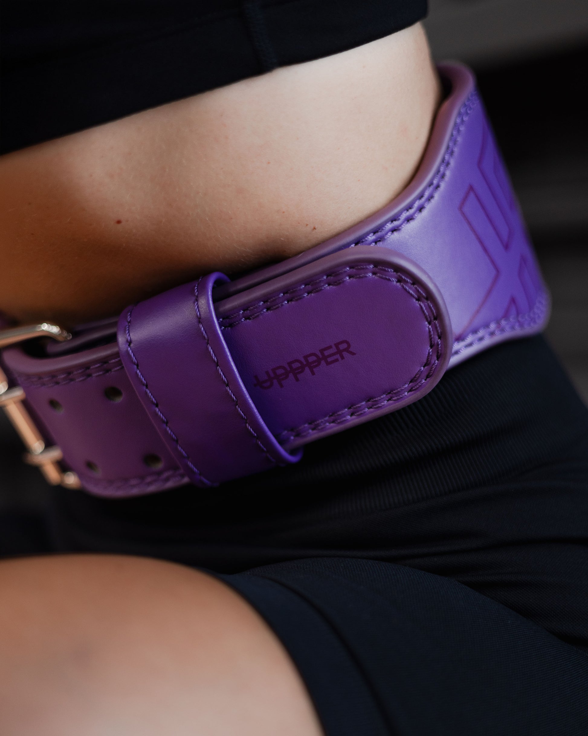close-up of uppper lifting belt in plum color showing stitching details and logo