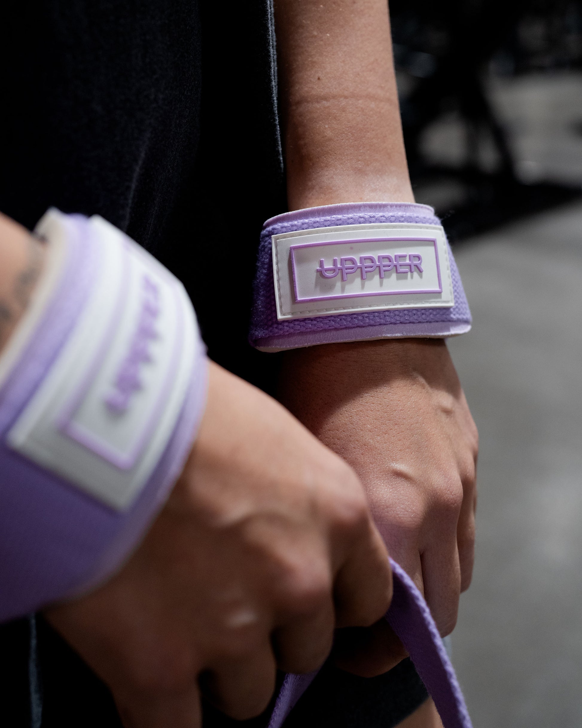 close-up of hands wearing purple lifting straps with uppper logo details