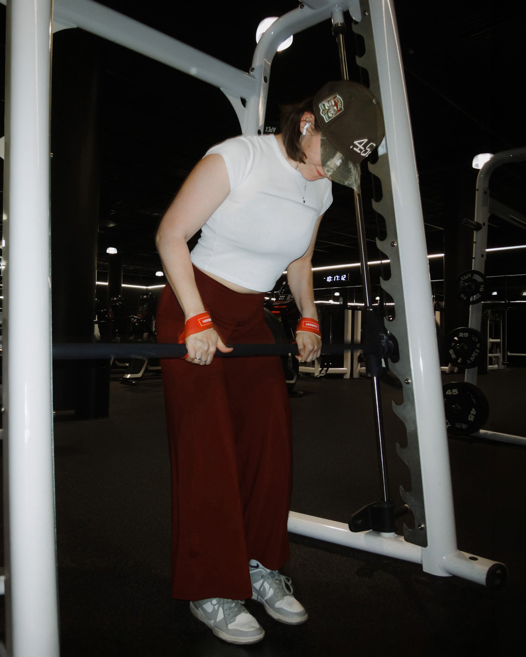 person exercising using red uppper lifting straps in a gym setting