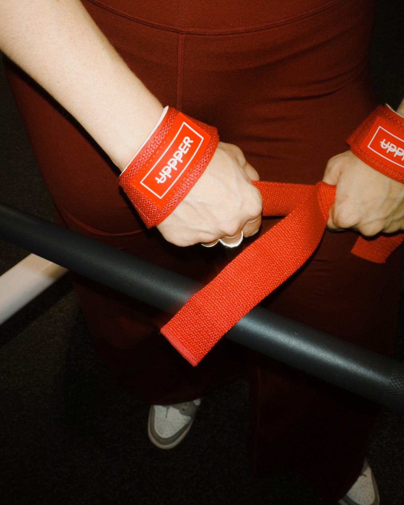 person using uppper lifting straps in red color on a dark background