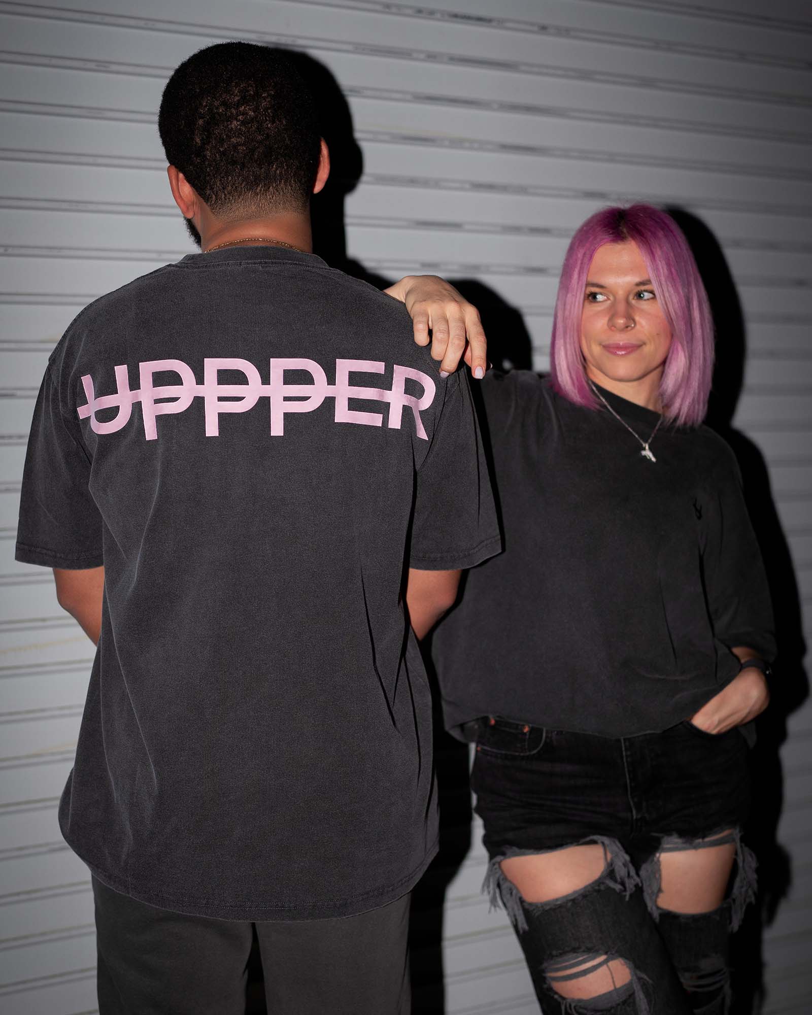 John and Iulia wearing uppper core t-shirts in washed black w/ pink logo