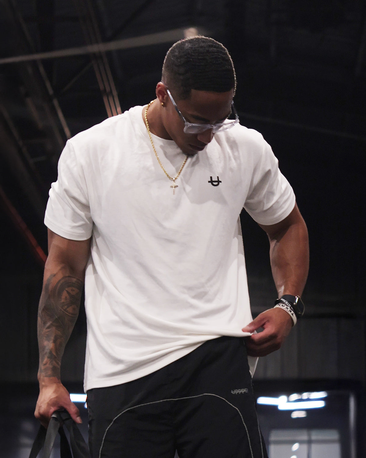 A man wearing a white uppper soft-stretch t-shirt and black uppper track pants,