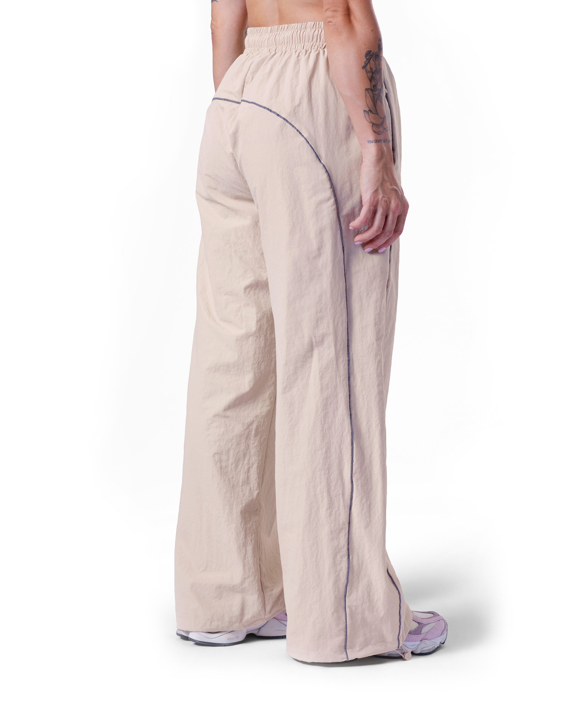 back of tan uppper track pants showing reflective lines on white background