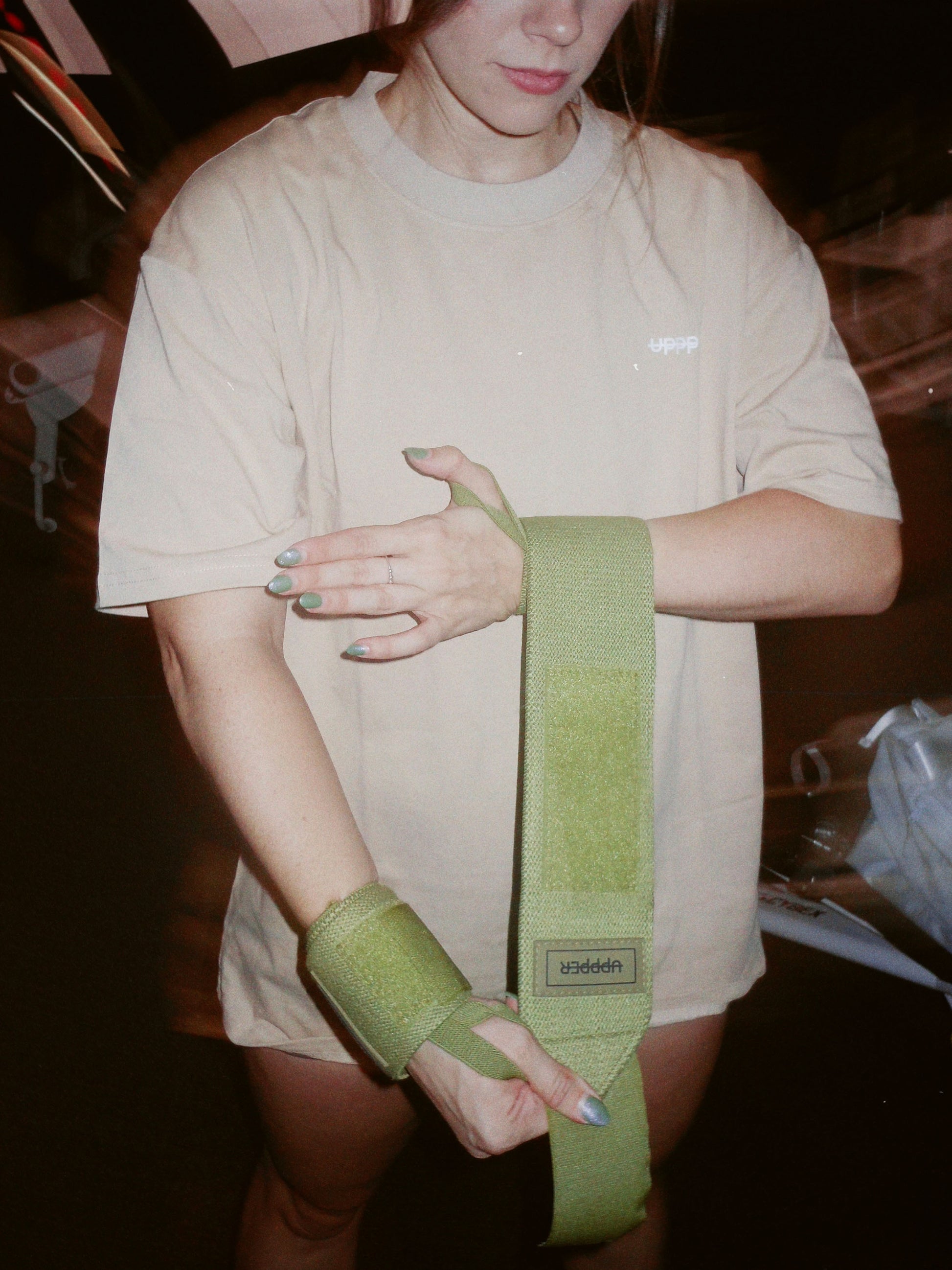 athlete wrapping khaki uppper wrist wraps  around wrist showing velcro detail thumb loop and logo 